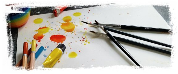 Splashed paint with brushes and pencils layed on paper
